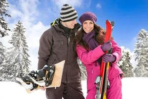 Couple standing on a snowy mountain in ski outfit