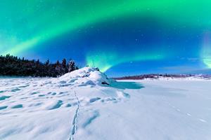 Northern lights in the dark blue sky over snowy ground