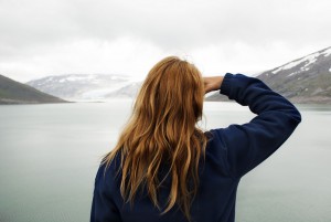 A Woman in Outdoor Look Watches at Glaciers in the Mountains