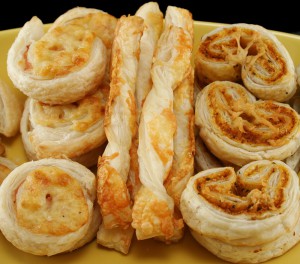 Savoury pastries including cheese straws, ham and cheese scrolls, and pesto and parmesan pastries.