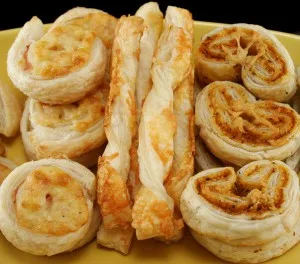 Savoury pastries including cheese straws, ham and cheese scrolls, and pesto and parmesan pastries.