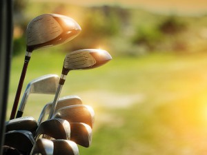 Golf clubs drivers with sun reflecting on them over green field background