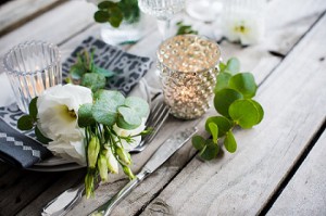 Table with white flowers, candles and glasses on old vintage wooden table. 