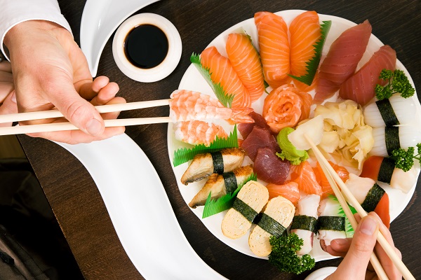 large plate of sushi rolls and japanese food being shared between two people