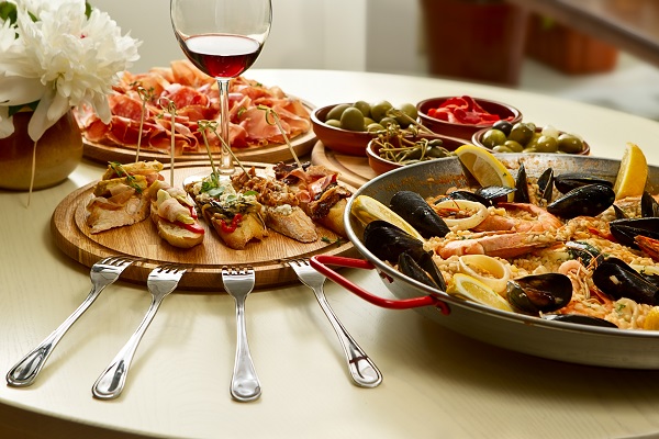 seafood served on a dinner table with a glass of wine and white flowers with four silver forks