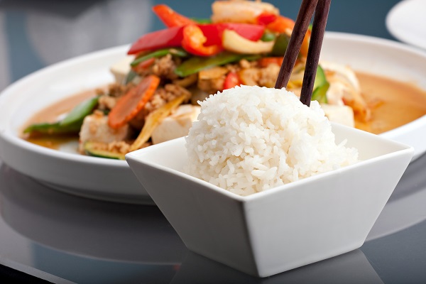 plate of thai food with side dish of jasmine rice with chopsticks