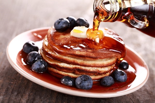 Canadian pancakes with blueberries being drizzled with syrup