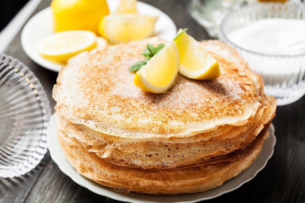 stacked pancakes topped with two lemon wedges